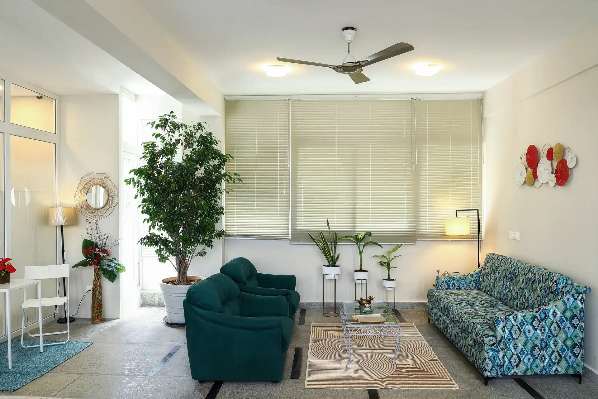 The patient lounge with teal armchairs, a patterned sofa and indoor plants