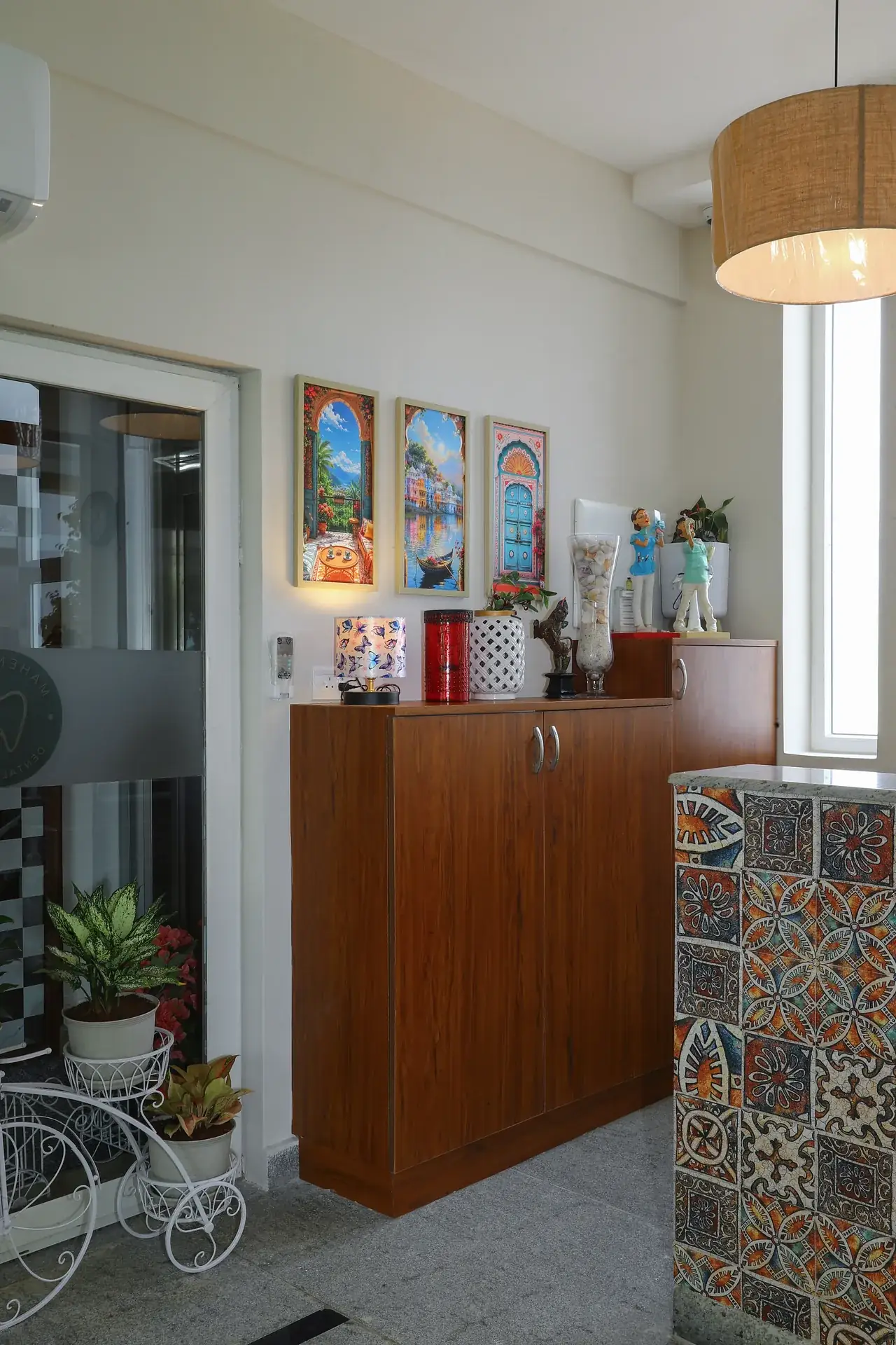 A wooden cabinet and tiled counter with potted plants in the reception area