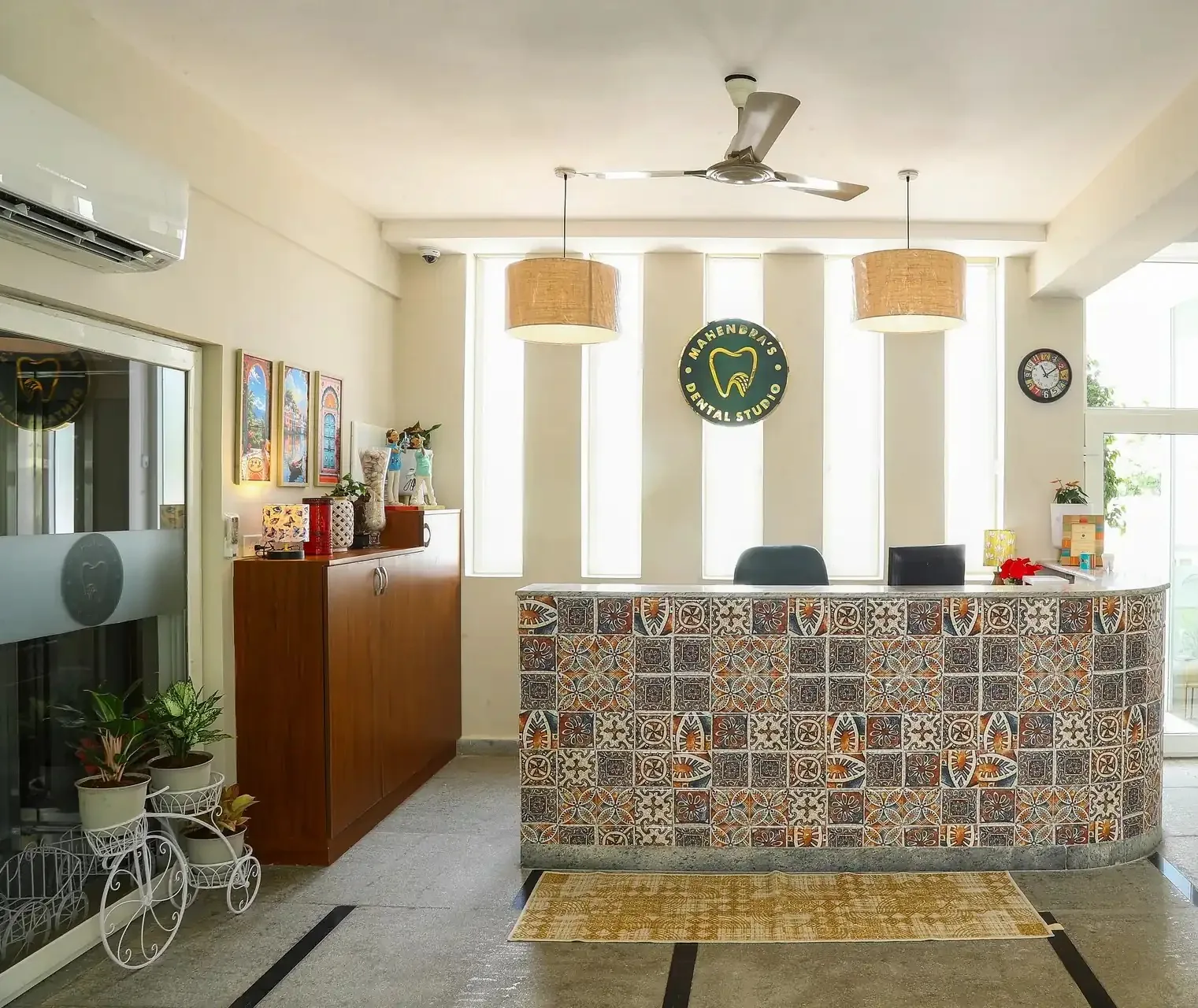 The reception at Mahendra's Dental Studio: a patterned-tile front desk under the clinic's logo sign and two pendant lights
