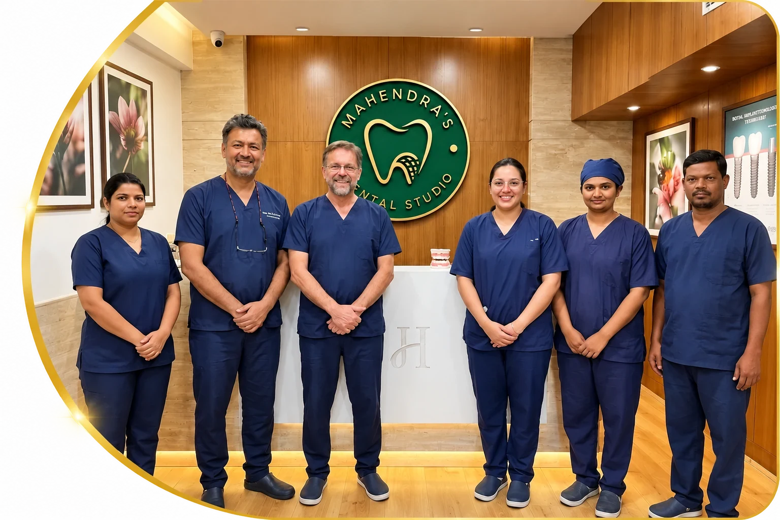 The Mahendra's Dental Studio team in navy scrubs at the reception, under the clinic's logo sign